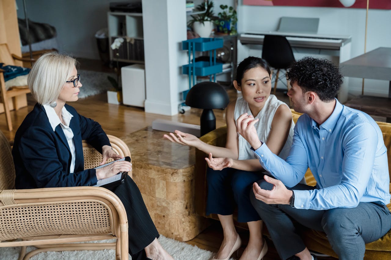 Couple having a discussion with a counselor in a modern living room setting.